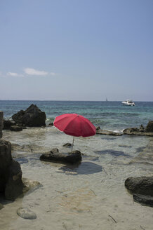 Spanien, Balearische Inseln, Ibiza, Las Salinas, Sonnenschirm auf einem Felsen - TKF000401