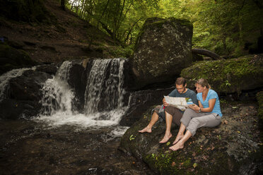 Germany, Rhineland-Palatinate, Moselsteig, Ehrbachklamm, couple reading map at waterfall - PAF000997