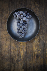 Schale mit tiefgefrorenen blauen Weintrauben auf Holz - LVF001946