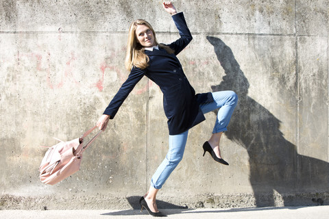 Junge Frau mit Samtblazer posiert vor einer Wand, lizenzfreies Stockfoto