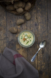 Glass of potato soup garnished with chives and croutons on wood - LVF001955