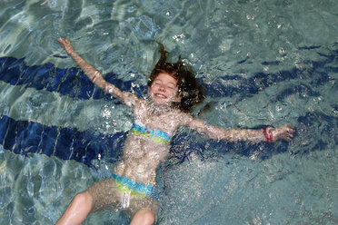 Lächelndes Mädchen schwimmt Rückenschwimmen in einem Pool - LBF000967