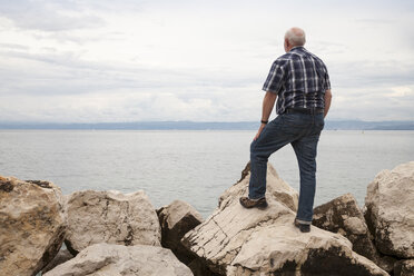 Slowenien, Piran, Mann steht auf Felsen am Ufer und schaut auf den Horizont - WIF001111