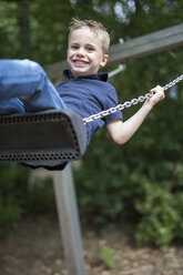 Portrait of smiling boy sitting on a swing - SHKF000001