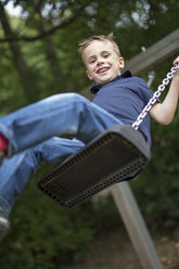 Portrait of smiling boy sitting on a swing - SHKF000003