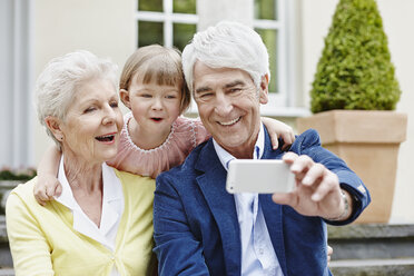 Germany, Hesse, Frankfurt, Senior couple taking selfie with granddaughter - RORF000052