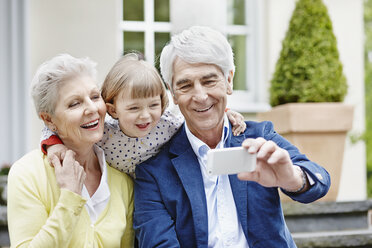 Germany, Hesse, Frankfurt, Senior couple taking selfie with granddaughter - RORF000053