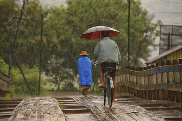 Myanmar, people on footbridge in monsoon rainfall - DSG000350