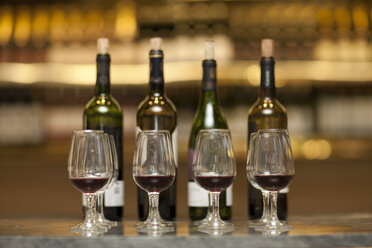 Red wine glasses and wine bottles on a counter of a wine cellar - ZEF001196