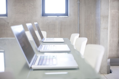 Reihe von drei Laptops auf einem Tisch in einem Büro, lizenzfreies Stockfoto