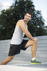 Sportsman doing stretching exercises on a staircase - MAD000060