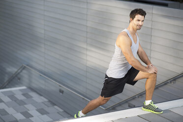 Sportsman doing stretching exercises on a staircase - MAD000061