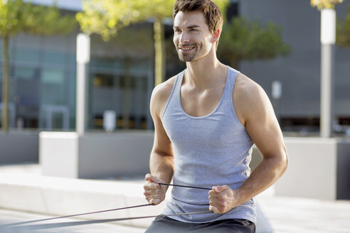 Portrait of smiling man training with fitness band - MAD000063