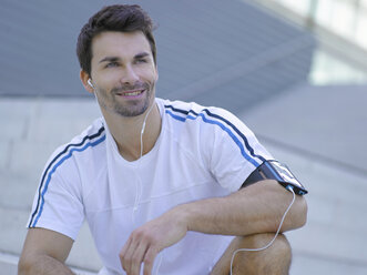 Portrait of smiling jogger with earphones - MAD000070