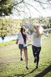 Two female friends running together in a park - ZEF001222
