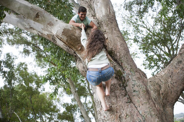 Teenager helping his girlfriend climing up a tree - ZEF001238