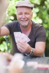 Lächelnder reifer Mann spielt Karten - ZEF001321