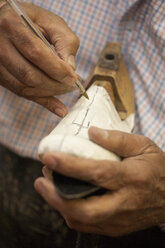Schuster, der mit einem Kugelschreiber Textilien auf Schuhleisten markiert - ZEF001246