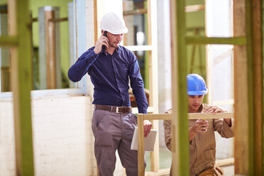Construction worker and foreman measuring wood frame - ZEF001820