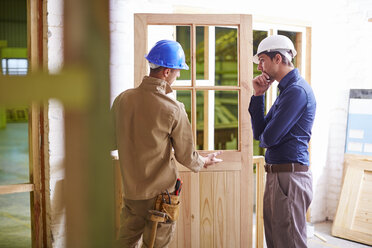 Construction worker and foreman discussing at wood frame - ZEF001959