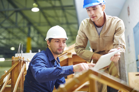 Bauarbeiter und Vorarbeiter diskutieren über Dachbalken, lizenzfreies Stockfoto