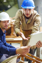 Construction worker and foreman discussing roof beams - ZEF001850