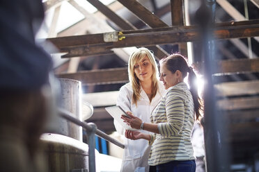 Two women in factory hall with digital tablet - ZEF001468