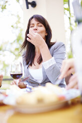 Frau genießt das Abendessen auf der Loggia - ZEF001475