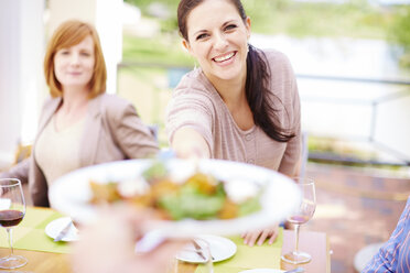 Smiling woman handing over plate - ZEF001478