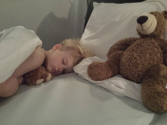 Kleiner Junge schläft mit Teddybär im Bett - MJF001495