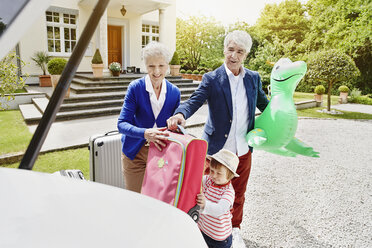 Grandparents with granddaughter and luggage on driveway - RORF000114