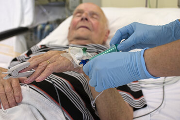 Entnahme einer Blutprobe bei einem älteren Mann, der nach einem Herzinfarkt auf der Intensivstation liegt - LA001085