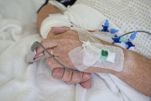 Hands of senior man with cannulae and band-aid being in intensive care - LAF001088