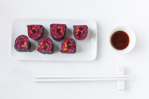 Teller mit Maki Sushi, Schale mit Sojasauce und Essstäbchen auf weißem Grund, lizenzfreies Stockfoto