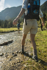 Österreich, Tirol, Tannheimer Tal, zwei junge Wanderer beim Überqueren von Wasser - UUF002099