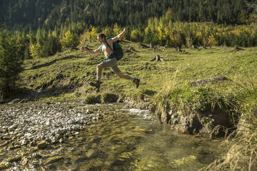 Austria, Tyrol, Tannheimer Tal, young hiker crossing water - UUF002130
