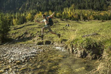 Österreich, Tirol, Tannheimer Tal, junger Wanderer beim Überqueren von Wasser - UUF002130