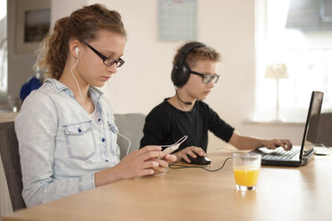 Bruder und Schwester mit Kopf- und Ohrhörern, die Laptop und Smartphone benutzen - PAF001004