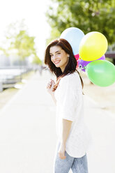 Porträt einer glücklichen jungen Frau mit einem Bündel Luftballons - GDF000481