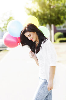 Lächelnde junge Frau mit einem Bündel Luftballons - GDF000482