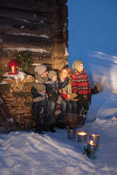 Happy family at wooden hut in snow - HHF004947