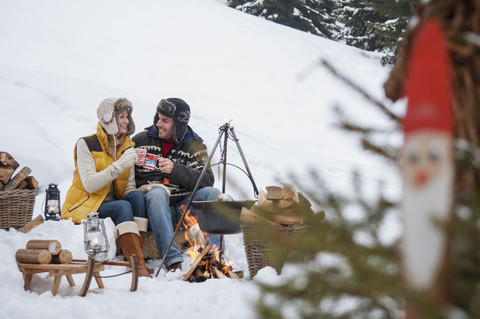 Smiling couple in snow at camp fire stock photo