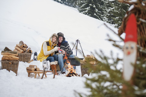 Smiling couple in snow at camp fire stock photo