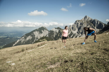 Österreich, Tirol, Tannheimer Tal, junges Paar streckt sich in den Bergen - UUF002055