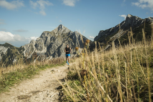 Österreich, Tirol, Tannheimer Tal, junger Mann beim Joggen in den Bergen - UUF002071