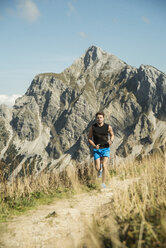 Österreich, Tirol, Tannheimer Tal, junger Mann beim Joggen in den Bergen - UUF002073