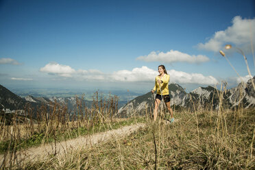Österreich, Tirol, Tannheimer Tal, junge Frau beim Nordic Walking in den Bergen - UUF002079