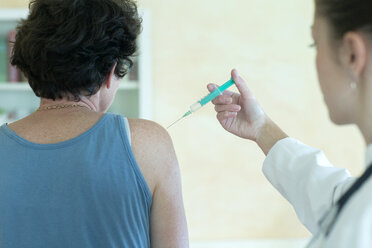 Young female doctor injecting in upper arm of a patient - SGF000865