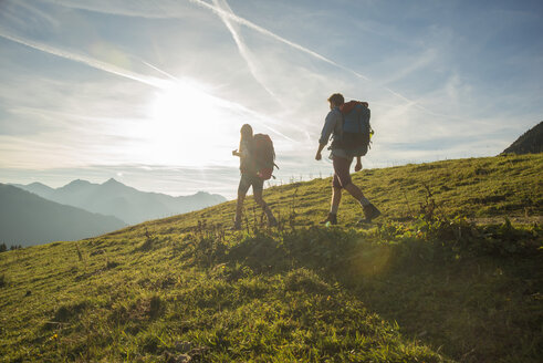 Austria, Tyrol, Tannheimer Tal, young couple hiking on alpine meadow - UUF002227