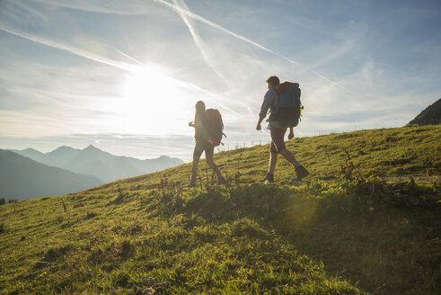 Österreich, Tirol, Tannheimer Tal, junges Paar wandert auf Almwiese - UUF002227